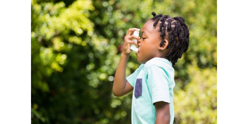 Young child uses an asthma inhaler while in profile.